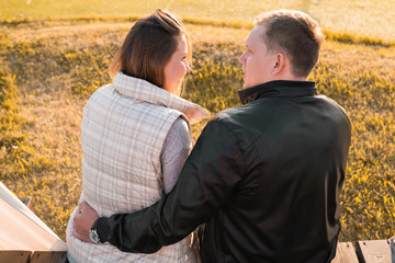Fototapeta premium Romantic young couple enjoying autumn nature sitting in a close embrace, view from behind