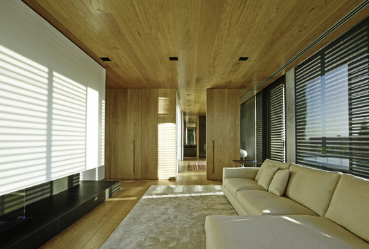 Spacious living room with modern off-white sectional couch. Floor to ceiling windows allowing a lot of natural light.
