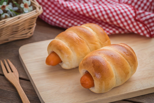 Bread rolls with sausage on wooden plate