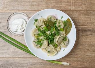 plate of traditional Russian dumplings sprinkled with herbs on wooden table