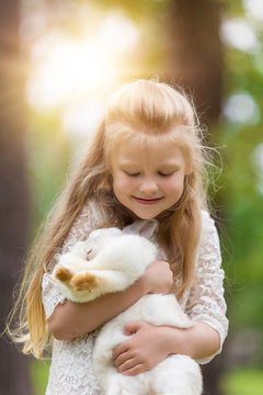 Little girl playing with white rabbit outdoor