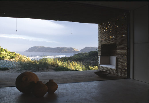 Open wall in modern  house with verandah and fitted recessed seat and with view over sand dunes