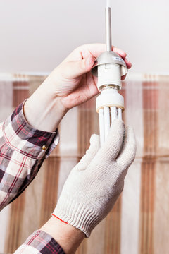 Electrician changing fluorescent lamp in holder