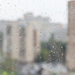 rain drops on window glass and blurred urban house