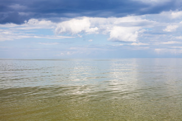 Fototapeta na wymiar calm green water of Azov Sea and cloudy sky