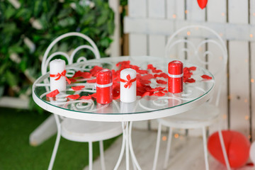 Romantic table with red hearts, rose petals and gift box