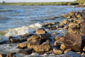 Waves beat crash on rocks on lake shore in a storm