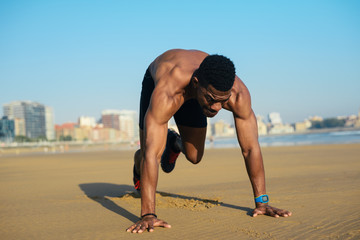 Mountain climbers exercise. Fit man warming up before running at the beach. Black athlete on hiit...