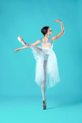 Ballerina in white dress posing on toes, studio background. © master1305