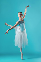 Fototapeta na wymiar Ballerina in white dress posing on toes, studio background.