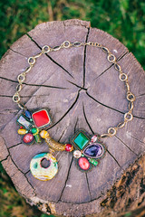 necklace on wood background outdoor. Jewelery with stones on stump.
