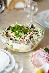 Meat snack for dinner on the dinner table. Salad with duck, mushroom, cucumber and plum with mayonnaise in a glass dish.