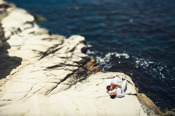 Bride lies on groom's shoulder resting on the sea shore