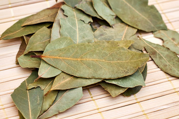Dry bay laurel leaves on bright wooden background