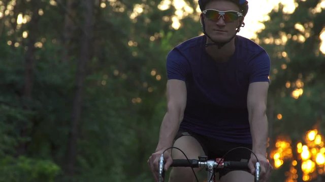 Cyclist riding a bike on an open road to the sunset