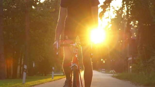 Cyclist riding a bike on an open road to the sunset