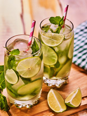 Alcohol drink. On wooden boards two glasses with alcohol drink and ice cubes. A drink number three hundred cocktail mohito with knife and mint leaf. Country life. Light background. Top view.