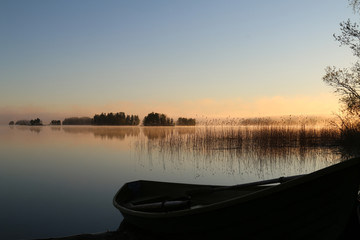 Sunrise on the lake with boat, haze.