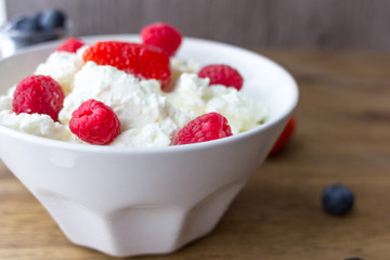 cottage cheese with berries on wooden table. healthy breakfast