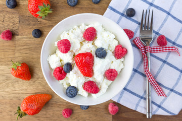 cottage cheese with berries and nuts on wooden table. healthy breakfast