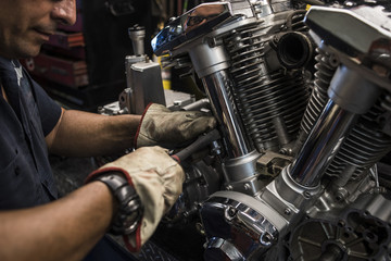 Close-up of mechanic fixing motorbike motor