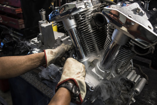 Close-up of mechanic fixing motorbike motor