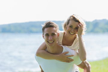 Man giving piggyback ride- carrying on the back his girlfriend