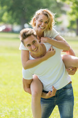 Man giving piggyback ride- carrying on the back his girlfriend