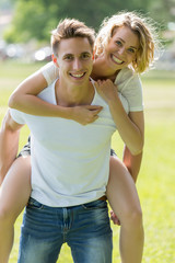 Obraz premium Man giving piggyback ride- carrying on the back his girlfriend