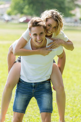 Obraz premium Man giving piggyback ride- carrying on the back his girlfriend