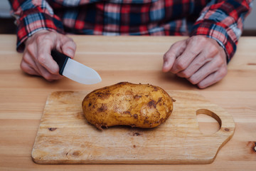 Man hands slicing fresh potato by ceramic knife