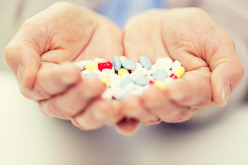close up of senior woman hands with pills