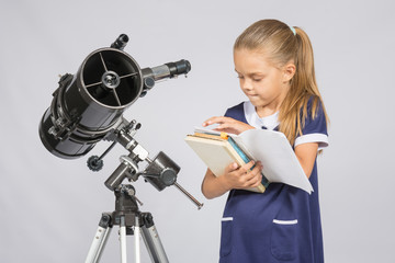 Schoolgirl astronomer leafing through books to find the right information at the stand of the...