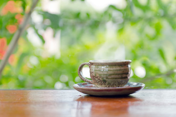 Hot coffee cup on the wooden table near garden