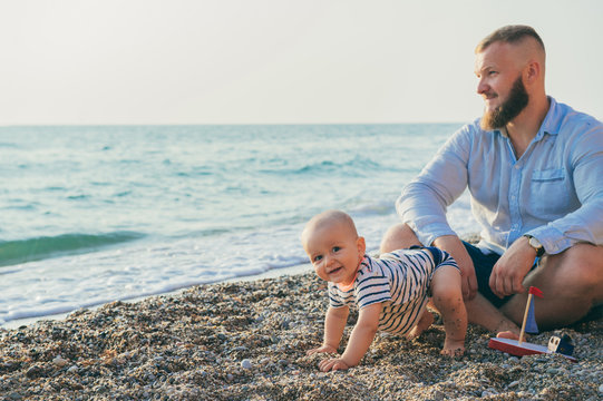 Dad With A Baby Boy Resting On The Beach