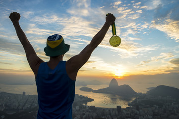 Gold medal champion athlete standing outdoors in silhouette at a golden sunrise skyline overlook in...