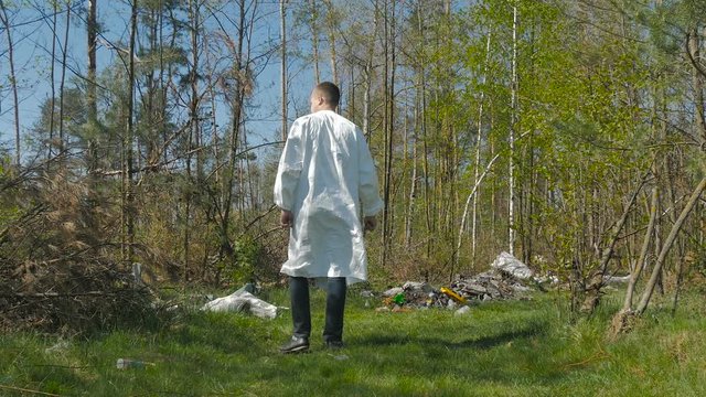 The guy goes through the woods among garbage heaps