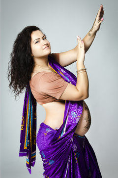 happy pregnant woman in Indian sari, belly and hands painted with henna