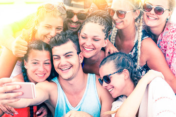 Cheerful group of friends having fun taking selfie at sunset on the beach - Joyful teenagers...