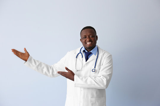 Professional African doctor on light background