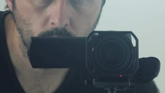Man behind camera directing and recording scene, video production enthusiast using digital camcorder to capture footage.