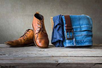 Men's clothing with t-shirt, blue jean and brown boots on wooden table over grunge background