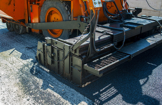 close-up details of industrial machinery working with asphalt, mixing bitumen with hot asphalt, layering on the road surface