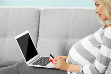 Pregnant woman shopping online on couch