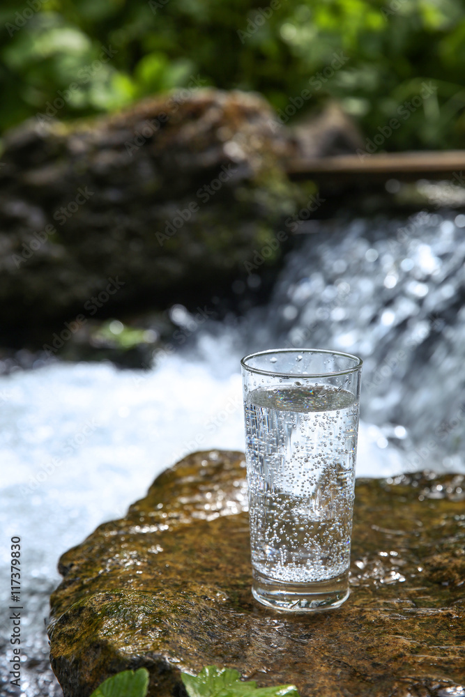 Sticker cup of water on small waterfall background