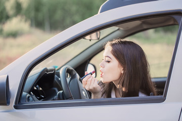 Woman putting lipstick in the car before date