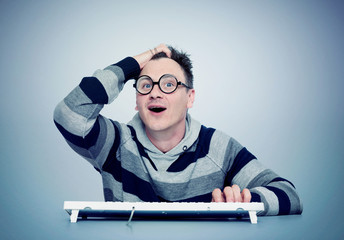 Funny man in glasses with keyboard in front of computer. Eureka! 