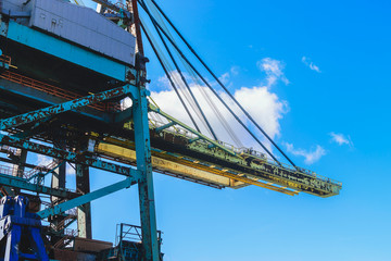 Cargo cranes in jetty over blue sky background.