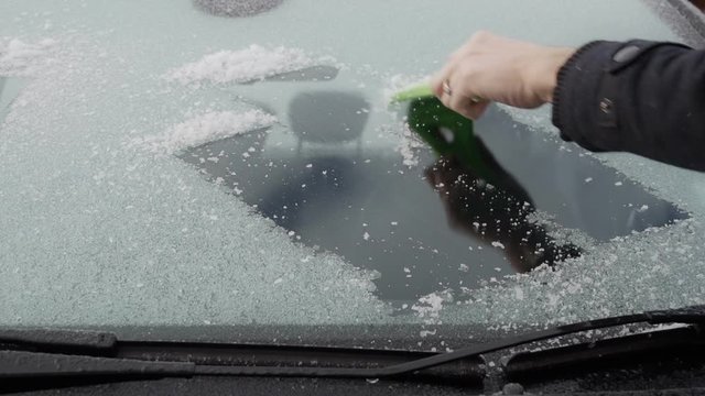 Male hand scraping ice off a cars windscreen. Filmed in super slow motion. Great Winter Background
