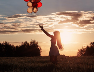 young women with balloons at sunset